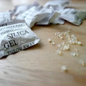 Silica gel packets and the beads that are in them sitting on a table.