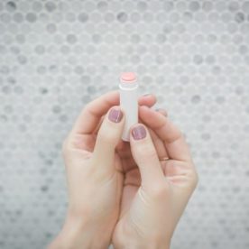 A girl holding up a stick of chapstick.
