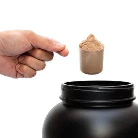 Someone taking a scoop of protein powder out of a container.