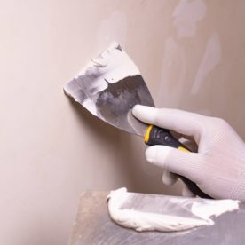 Someone spreading spackle across a wall.