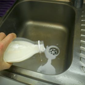 Someone dumping spoiled milk down the drain.