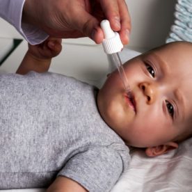 A parent gives their infant some gas drops through a dropper.