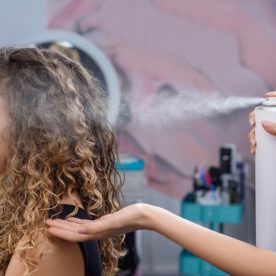 A hair dresser spraying a client's hair with hair spray.