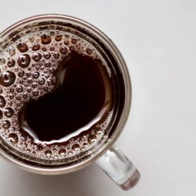 a cup of black coffee that contains caffeine on a white table.
