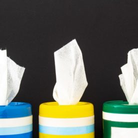 Three canisters of disinfectant wipes on a black background.