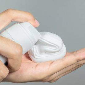 Someone dispenses shaving cream onto their palm.
