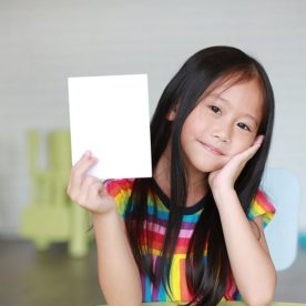 A young child holds up a piece of paper.