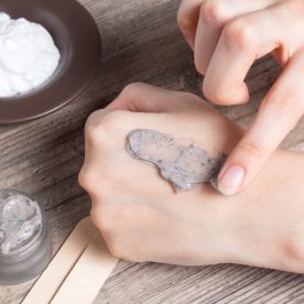 A woman puts a small amount of exfoliating scrub on the back of her hand.