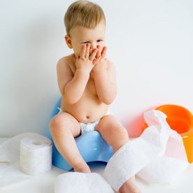 Toddler sitting on practice toilet with urine in it.