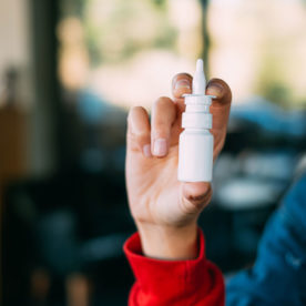 someone holding a nose spray that has Flonase ® in it