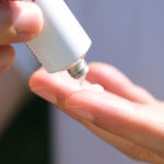A woman squeezing out Triamcinolone Acetonide Cream on her finger tips.