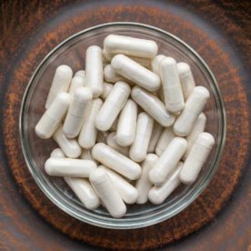 an image of kava kava capsules in a wood bowl.
