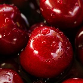An up-close image of fresh cherries with water droplets.