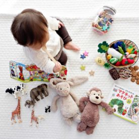 A toddler sitting on a play mat with an array of toys and items that are foreign bodies.
