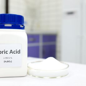 A canister of boric acid sits besides a small dish of boric acid cream on a doctors table.