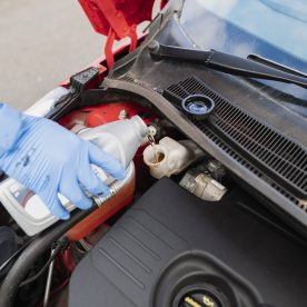 person pouring brake fluid into car