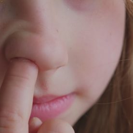 Young girl picking her nose for boogers
