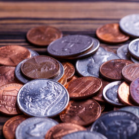 A pile of US coins with pennies, quarters, dimes, and nickels on a table.