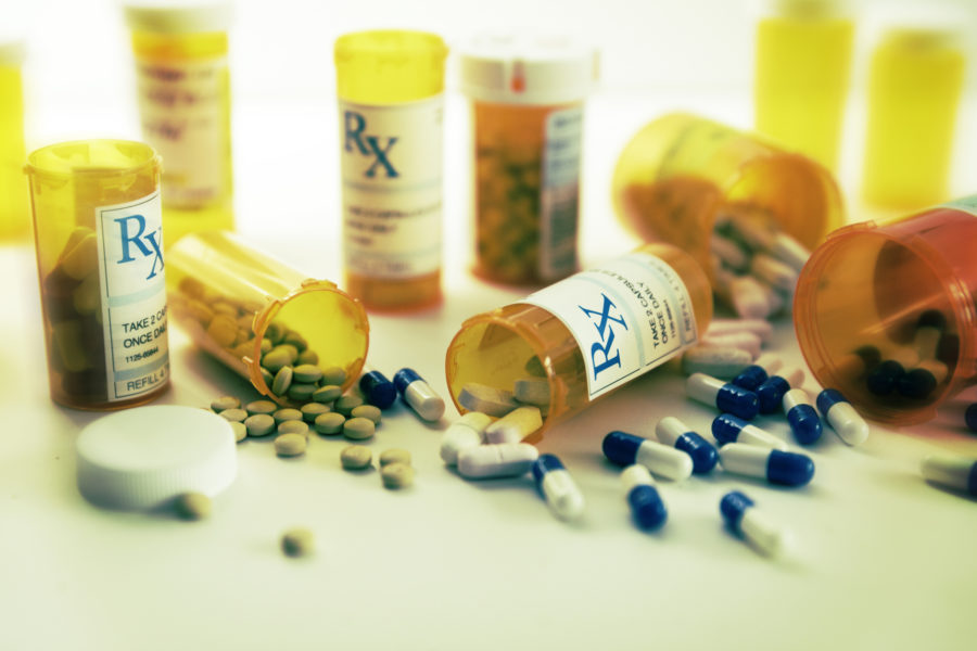 Capsules Of Different Types Of Medicines Sitting On A White Table.