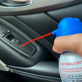 An air duster being used to clean a car interior.