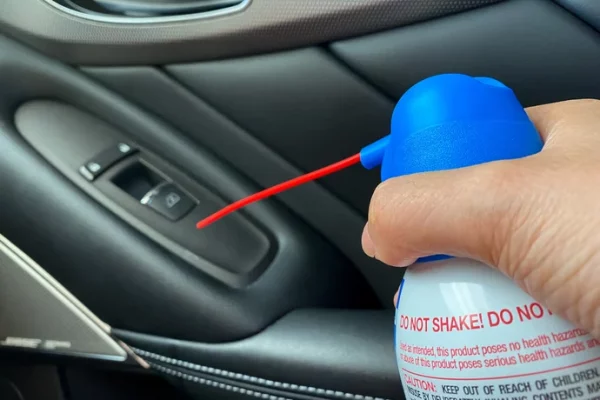 An air duster being used to clean a car interior.