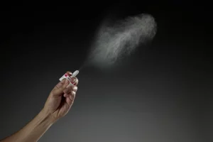 Narcan nasal spray is sprayed across a black background.