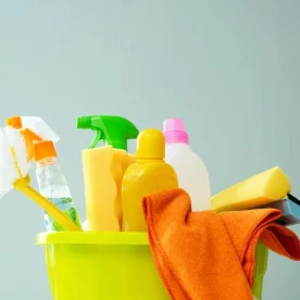 A bucket full of disinfectant cleaners, brushes, and cloths.
