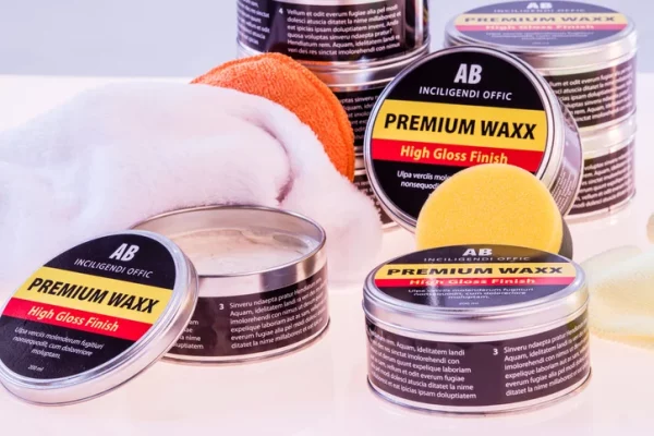 Tins of car wax beside foam applicators.