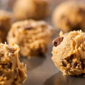 Many raw cookie dough balls on a baking tray.