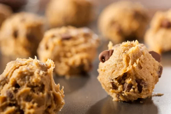 Many raw cookie dough balls on a baking tray.