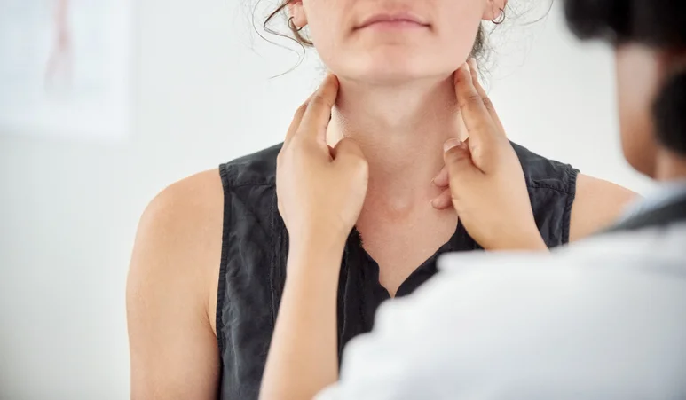 A doctor checks a woman's thyroid.