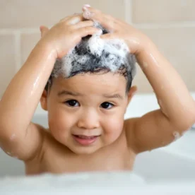 A baby washes their hair with shampoo.