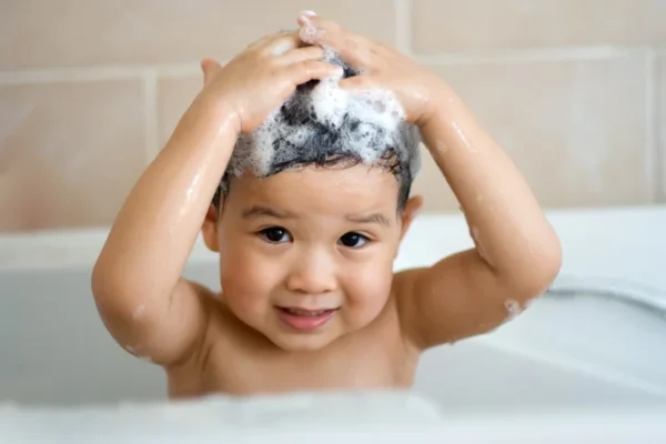A baby washes their hair with shampoo.