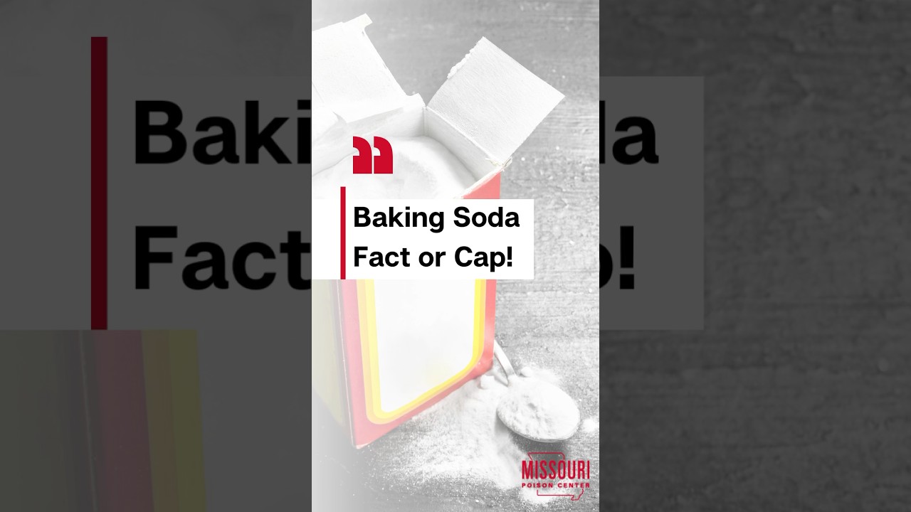 Opened baking soda box on a gray table that also has a spoon full of baking soda