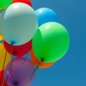 A cluster of colorful helium balloons against a blue sky.