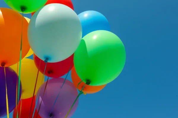 A cluster of colorful helium balloons against a blue sky.
