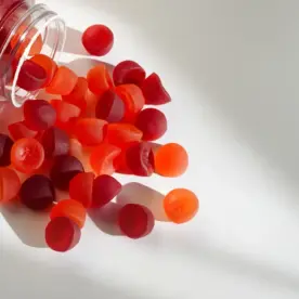 A jar of red iron gummies spills onto a table.