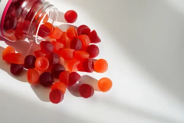 A jar of red iron gummies spills onto a table.
